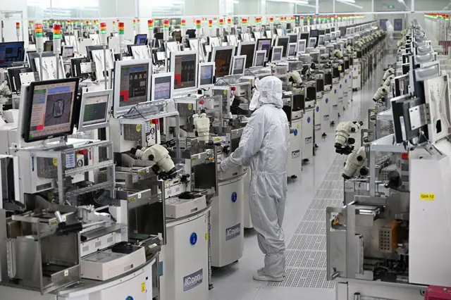 一名技术人员在中国东部江苏省宿迁市的一家半导体制造工厂内操作芯片加工设备